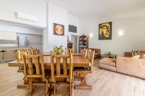 Ein geräumiger Wohnbereich mit einem Holzessttisch, einer Couch und einem an der Wand befestigten Fernseher.