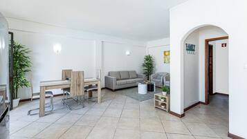 Una sala de estar moderna con comedor, un sofá gris y una pequeña mesa con una planta.