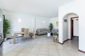Ein modernes Wohnzimmer mit Essbereich, einem grauen Sofa und einem kleinen Tisch mit Pflanze.
