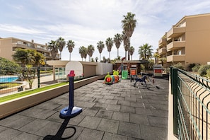 Ein Spielplatz mit Basketballkorb, Fitnessgeräten und im Hintergrund Palmen.