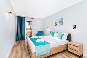 Ein Schlafzimmer mit einem Bett, einem Nachttisch, einem Stuhl, einem Fenster mit Vorhängen und einem Wandbild.