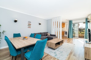 A modern living room with a dining area, a gray sofa, teal chairs, and a wooden coffee table. - Portim o Resort Private Parking Pool (Portimão)