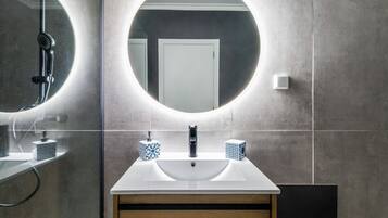 Un baño con un espejo redondo, un lavamanos blanco y dos dispensadores de jabón estampados.