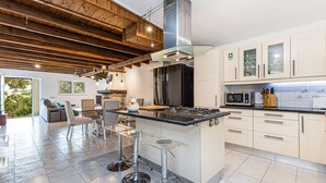 Una cocina moderna con una isla central, electrodomésticos de acero inoxidable y una zona de comedor con sofá y sillas.