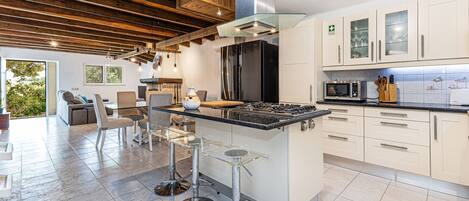 A modern kitchen with a central island, stainless steel appliances, and a dining area with a sofa and chairs.