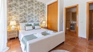 Ein Schlafzimmer mit Bett, Nachttischen, einem Badezimmer und einer Holztür.