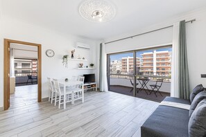 Een modern appartement met een balkon, een eethoek en een woonkamer met een bank.