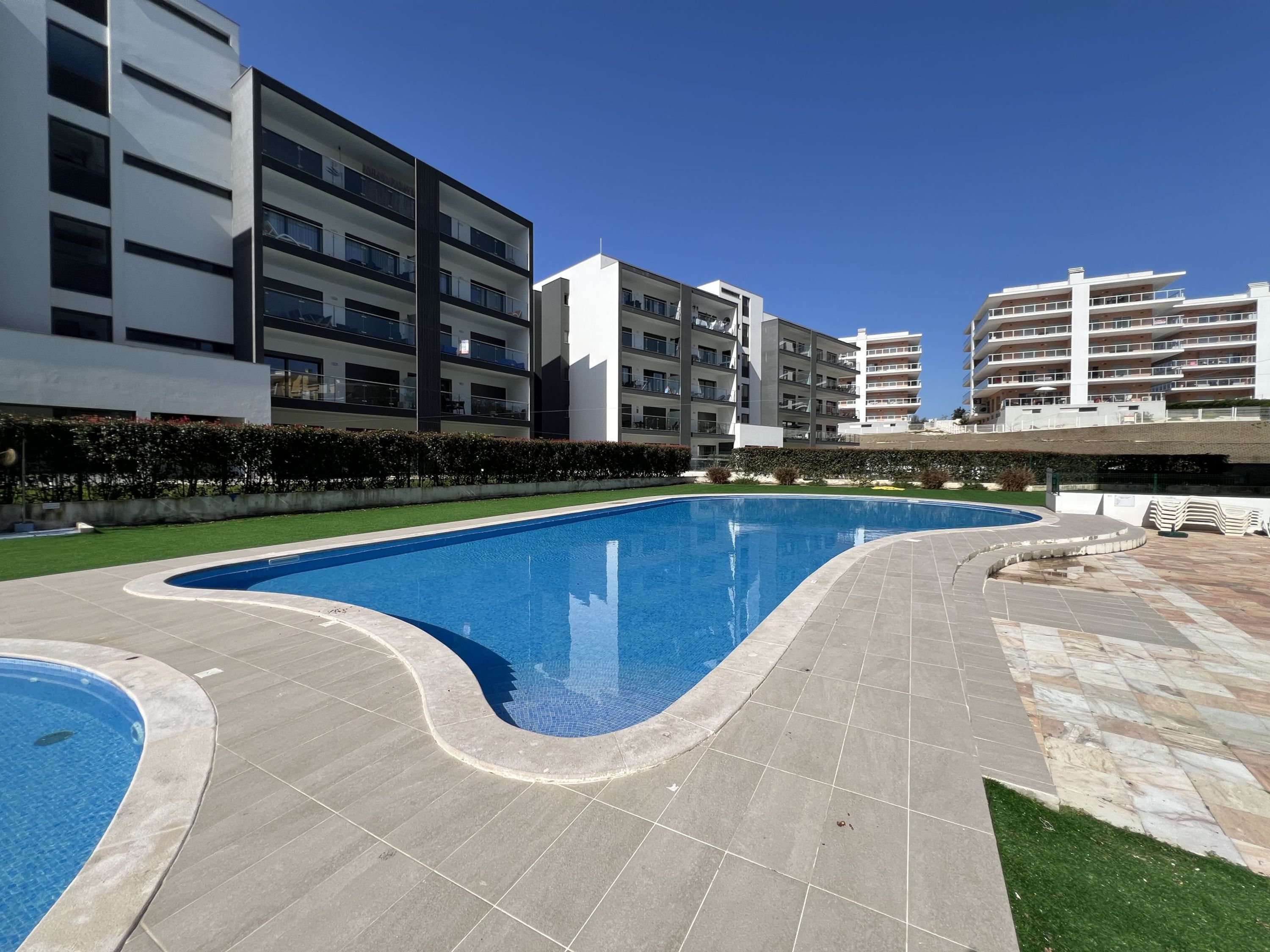 A modern residential building with a swimming pool, flat roof, and balconies.