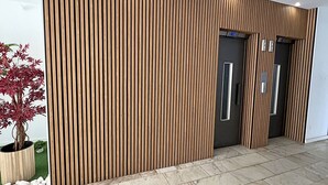 A modern building facade with vertical wooden slats, a potted plant, and a tiled floor. - Praia da Rocha Pet Friendly By the Beach (Portimão)