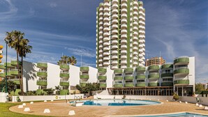 Un hôtel de grande hauteur doté de nombreux balcons, d’une piscine et d’une pelouse bien entretenue.