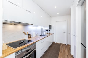 A modern kitchen with white cabinets, a wooden countertop, stainless steel appliances, and a tiled backsplash. - Torre Verde Sea View Apartments 906 (Portimão)