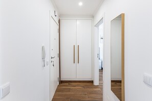 Ein Flur mit einer weißen Tür, einem Holzboden und einem Spiegel an der rechten Wand.