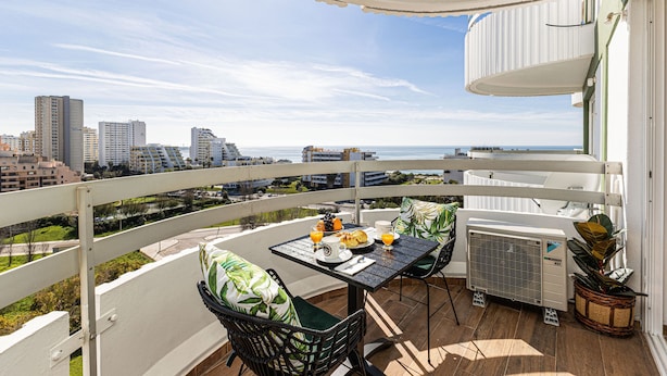 Un balcon avec une table préparée pour le petit-déjeuner, une chaise et un appareil de climatisation.