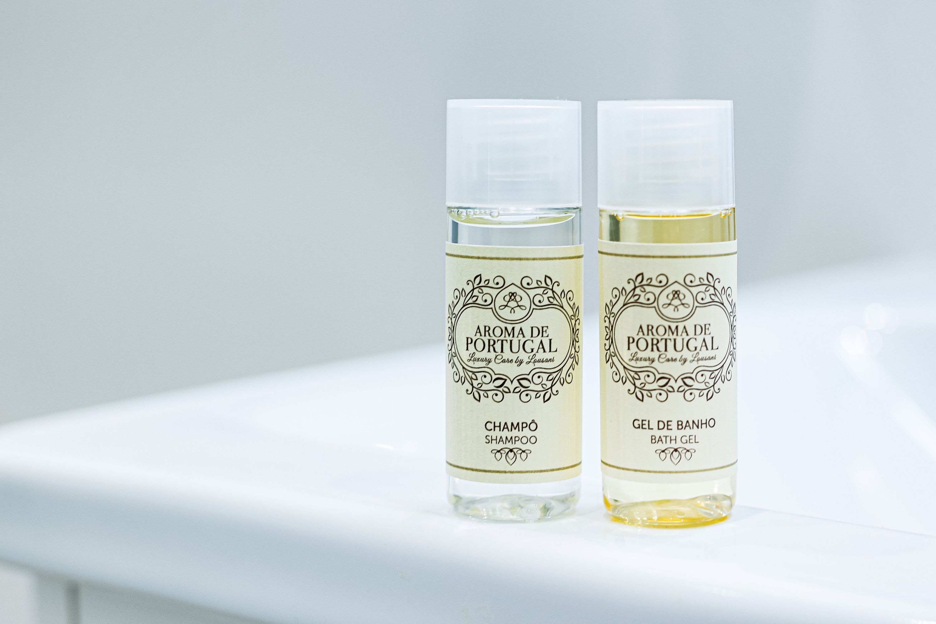 Two bottles of 'Aroma de Portugal' shampoo and bath gel on a white surface.