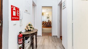 Ein Flur mit einem Feuerlöscher, einer Blumenvase und einem Essbereich im Hintergrund.
