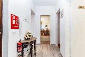 Ein Flur mit einem Feuerlöscher, einer Blumenvase und einem Essbereich im Hintergrund.