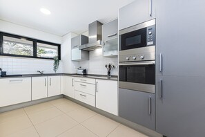 Uma cozinha moderna com eletrodomésticos de aço inoxidável, armários brancos e uma janela que oferece luz natural.