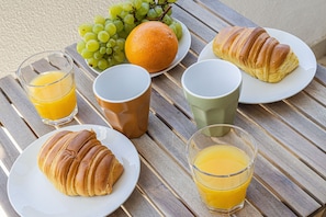 A breakfast setting with croissants, fruit, and orange juice on a wooden table. - Pateo da Rocha in Portim o (Portimão)