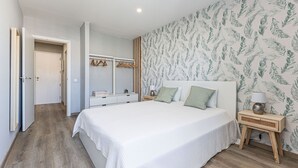 Un dormitorio con una cama grande, mesitas de noche, un armario y un espejo.