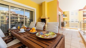 A balcony with a wooden table, chairs, and a bowl of fruit. - Pateo do Convento in Lagos (Lagos)