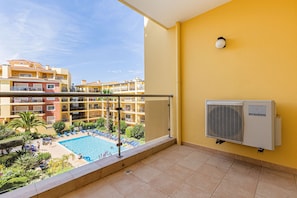 Ein Balkon mit Blick auf einen Swimmingpool, eine Klimaanlage und einen klaren Himmel.