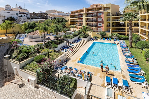Ein Hotel mit Schwimmbad, Liegestühlen und einem Garten.