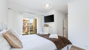 A bedroom with a bed, a flat-screen TV, a dresser, a window with curtains, and a balcony view. - Pateo do Convento in Lagos (Lagos)