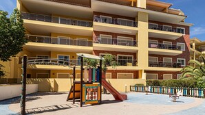A multi-story building with balconies, a playground with a slide, and a pool area. - Pateo do Convento in Lagos (Lagos)