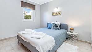 Ein Schlafzimmer mit Bett, Nachttisch, Fenster mit Blick und einer Wandleuchte.