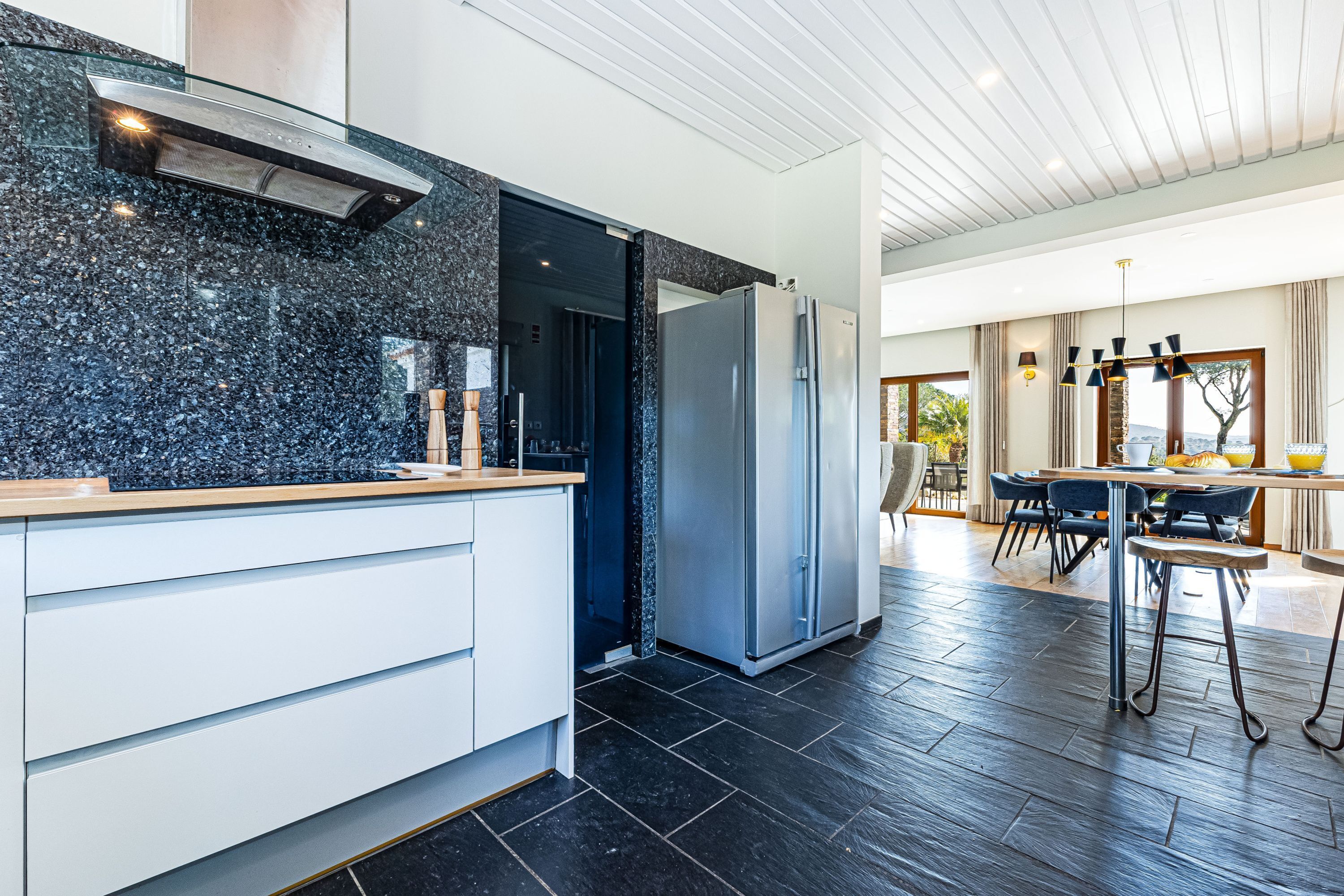 Eine moderne Küche mit Granit-Arbeitsplatte, Edelstahlgeräten und einem Essbereich mit Tisch und Stühlen.