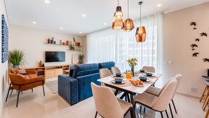 A modern living room with a blue sofa, dining table with chairs, and pendant lights. - Adega Luxury Near Lagos City Center With Pool (Lagos)