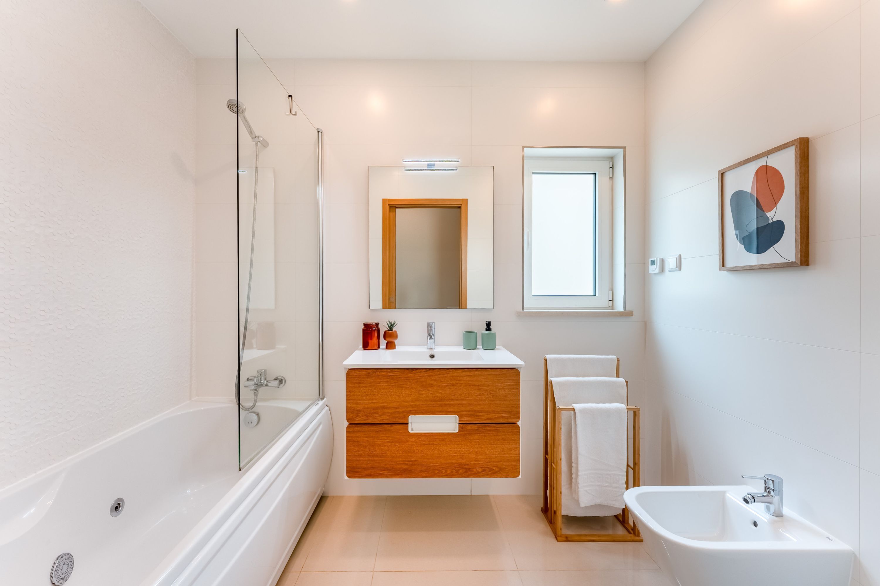 A modern bathroom with a glass-enclosed shower, a wooden vanity with a mirror, and a freestanding bathtub.
