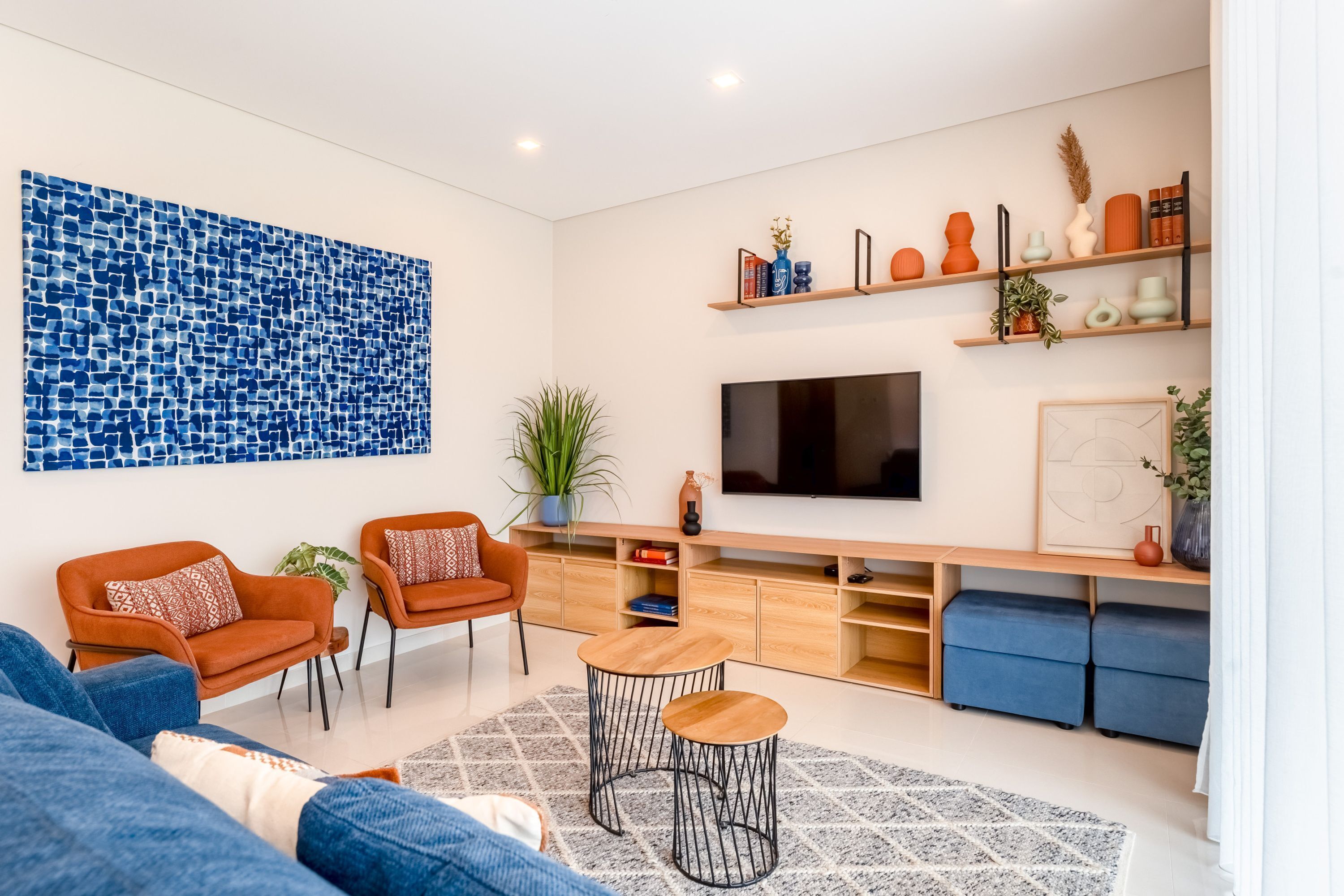 Un salon moderne avec un téléviseur, des canapés, une table basse et un mur décoré d’un motif.