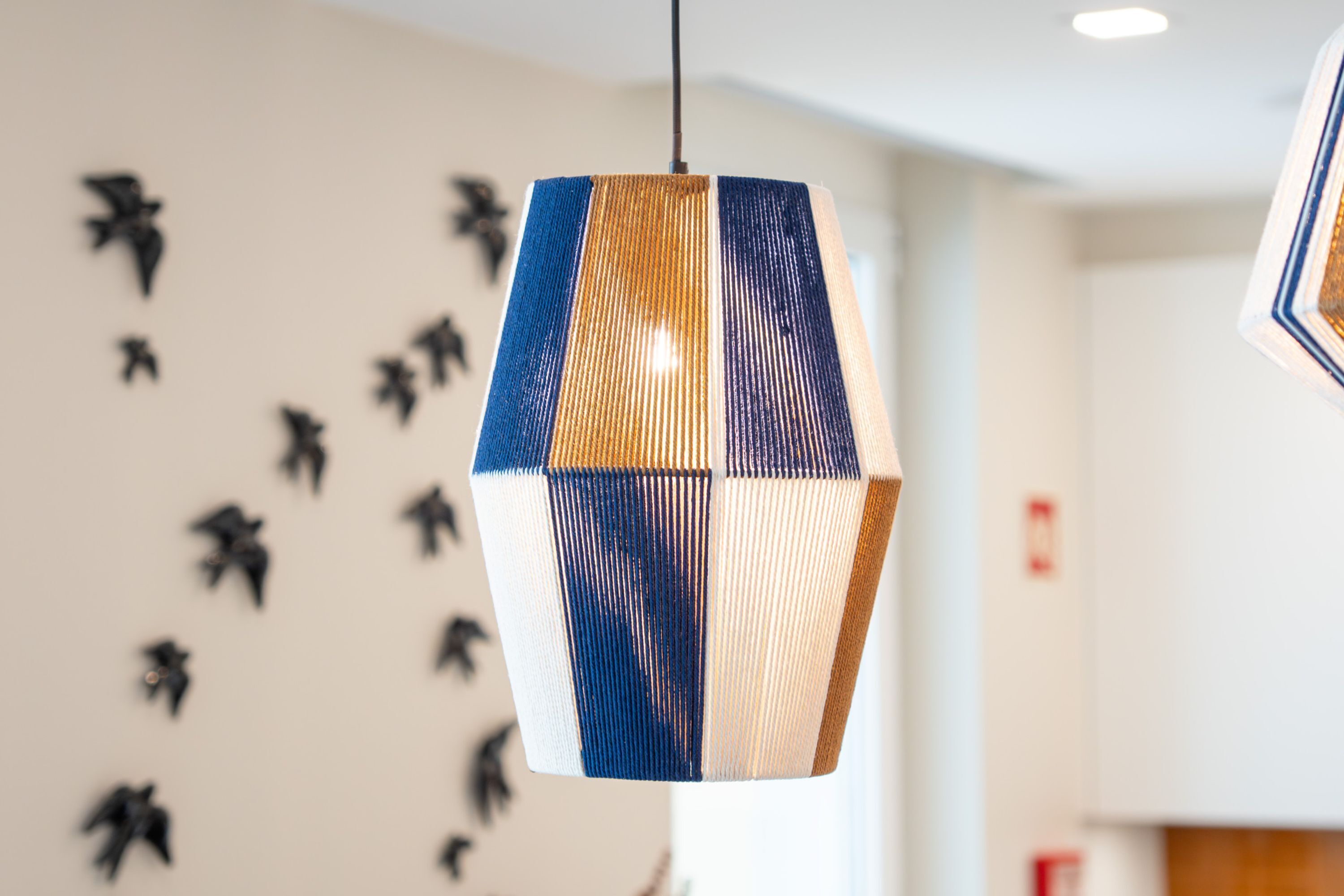 Un luminaire suspendu de forme hexagonale, orné d’un motif à rayures.