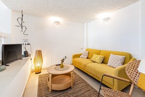 A modern living room with a yellow sofa, a round wooden coffee table, a TV, and a unique wall art piece. - Casa Saudade Townhouse - 400m From The Beach (Lagoa)