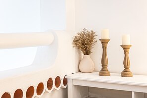 A white wall with a window, a vase with dried flowers, and two candle holders with candles. - Casa Saudade Townhouse - 400m From The Beach (Lagoa)
