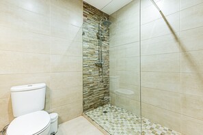A bathroom with a shower, toilet, and a tiled floor. - Cozy Place Lagos Apartment Beach Couples Nom (Lagos)