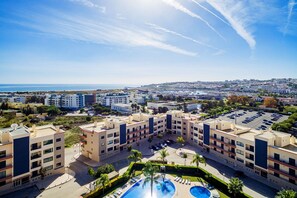 Ein Hotelkomplex mit mehreren Gebäuden, einem Schwimmbad und Blick aufs Meer.