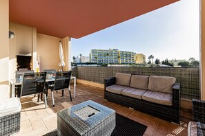 Ein Balkon mit Esstisch, Stühlen, einer Couch und einem Fernseher.