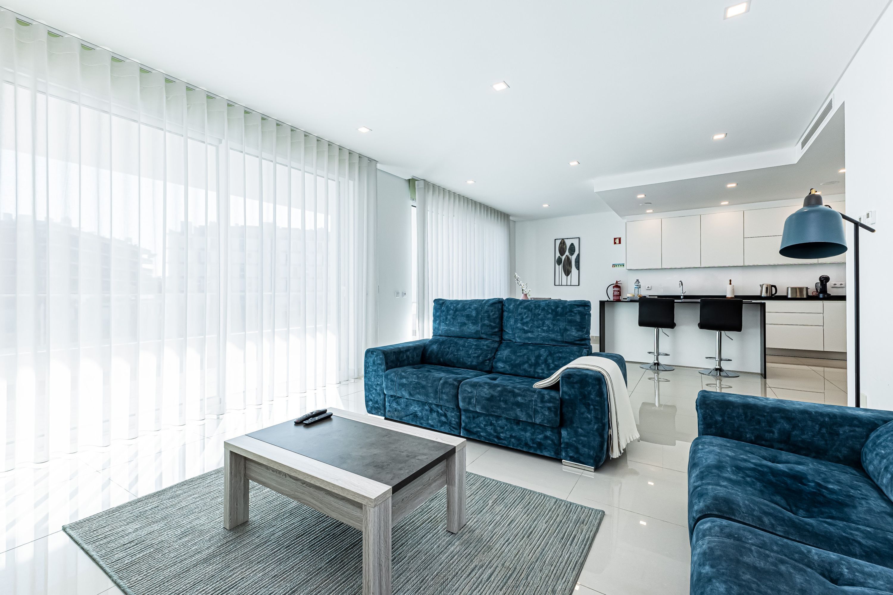 Una sala de estar moderna con un sofá, una mesa de centro y una cocina al fondo.