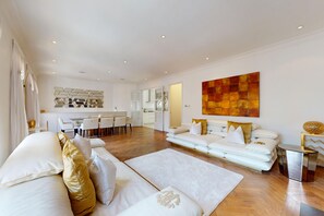 Ein modernes Wohnzimmer mit einer Couch, einem Couchtisch und einem Essbereich mit Tisch und Stühlen.