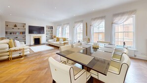 A spacious living room with a fireplace, a dining area, and a sofa set. - Central 2BR Home Steps to Kensington Palace & Hyde park (London)
