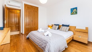 A bedroom with a bed, wooden wardrobe, bedside table, and an air conditioning unit. - Joia Da Rocha Beach Parking (Portimão)