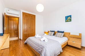 Ein Schlafzimmer mit Bett, Holzschrank, Nachttisch und Klimaanlage.
