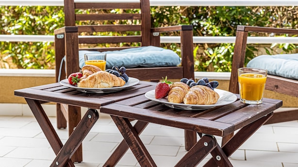 A wooden table with plates of croissants, strawberries, and blueberries, and a glass of orange juice. - Joia Da Rocha Beach Parking (Portimão)