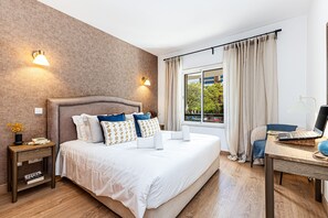Ein Hotelzimmer mit Bett, Nachttischen, einem Schreibtisch mit Laptop und einem Fenster mit Vorhängen.