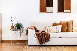 A white sofa with a brown throw blanket, a small table with a plant, and two framed documents on the wall. - Marina Garden View in Lagos (Lagos)