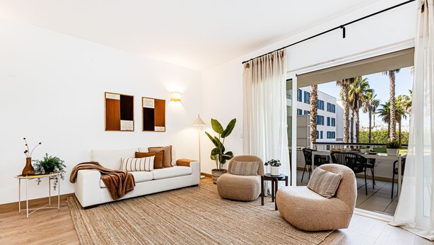 A modern living room with a white sofa, a beige armchair, a large rug, and a view of the outdoors through a sliding glass door. - Marina Garden View in Lagos (Lagos)