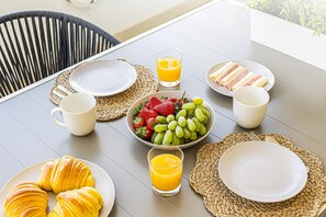 A breakfast table with plates, a bowl of fruit, croissants, and glasses of orange juice. - Marina Garden View in Lagos (Lagos)