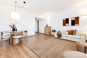 A modern living room with a wooden dining table, a white sofa, and a large rug. - Marina Garden View in Lagos (Lagos)